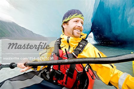 Man kayaking amongst large icebergs near Bear Glacier in Resurrection Bay near Seward, Alaska