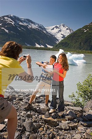 Children pose with ice chunk along shore of Portage Lake on hike Chugach National Forest, AK