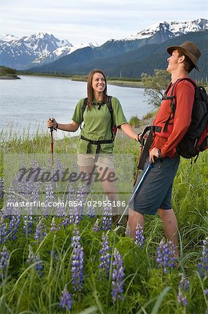 Young couple hiking through a field of Lupine flowers along the 20 Mile river Southcentral Alaska Summer