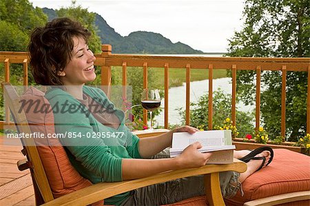 Gast liest & entspannt in einem Liegestuhl Redoubt Bay Lodge im Bereich Big River Seen. Redoubt Bay State Lebensraum Problembereich, Kenai, Alaska