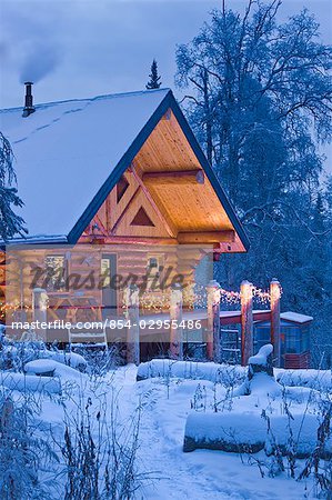 Log Cabin in the woods decorated with Christmas lights at twilight near Fairbanks, Alaska during Winter