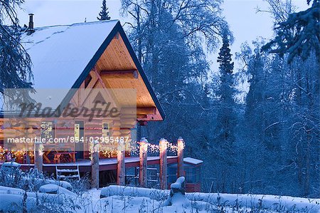 Cabane dans les bois décoré de lumières de Noël au crépuscule près de Fairbanks en Alaska pendant l'hiver