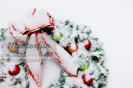Close up of a snowcovered Christmas wreath with a red bow lying in the snow in Fairbanks, Alaska