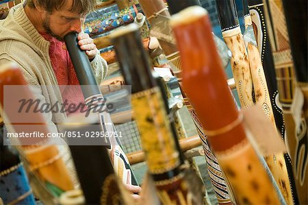 Man playing didgeridoo at stall in market,Sydney,New South Wales,Australia