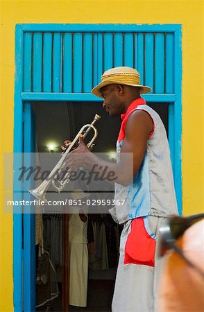 A street entertainer playing a trumpet beside colorful doorway,Havana,Cuba