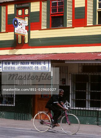 Man cycling past shops,Grenville,Grenada.