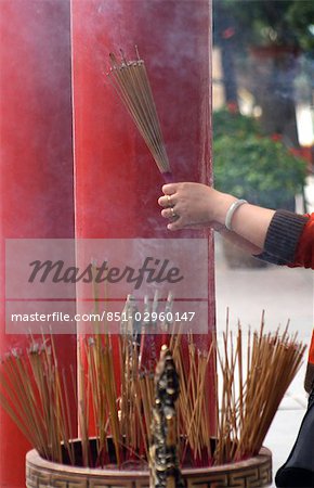 Frau holding Bunch of Rauchen Weihrauch klebt an Wong Tai Sin Temple, Hong Kong, China