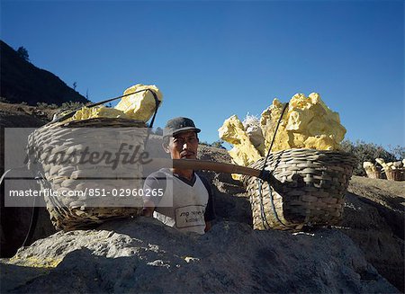 Worker with baskets of yellow sulphur,Kaweh Idjen,Java,Indonesia