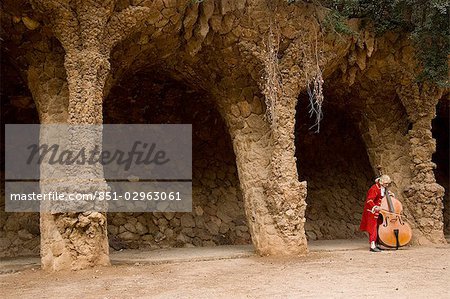 Mann im Kostüm spielt Violoncello im Park Güell, Barcelona, Katalonien, Spanien