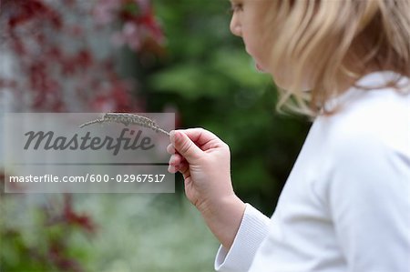 Jeune fille tenant une chenille sur un bâton