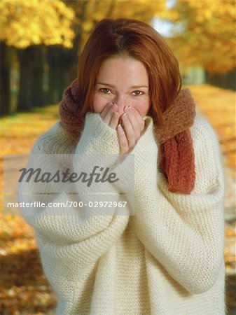 Portrait d'une femme portant le chandail et couvrant la bouche avec des mains, à l'extérieur en automne