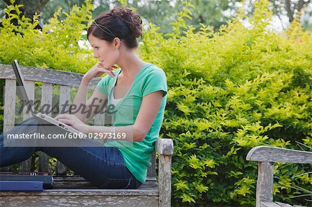 University Student Sitting on a Bench Using a Laptop Computer