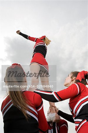 Cheerleaders holding girl up