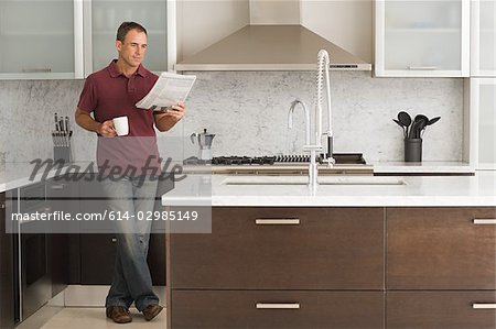 Man reading a newspaper in kitchen