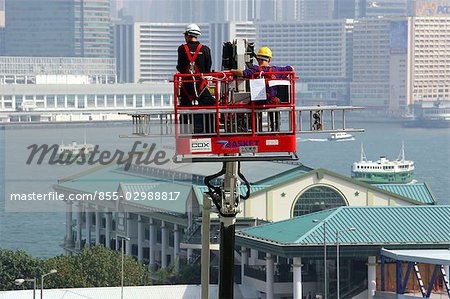 Cleaning worker on the cradle hoist with background of Central Pier, Central, Hong Kong