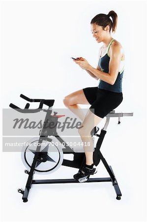 Woman Using Cell Phone While Riding Stationary Bicycle