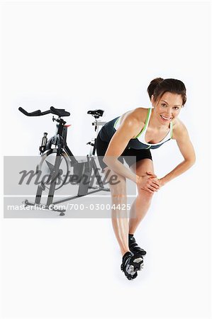 Femme qui s'étend de la bicyclette stationnaire