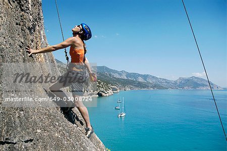 Rock femme escalade, baie en arrière-plan