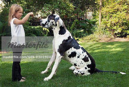 Girl holding up biscuit for dog