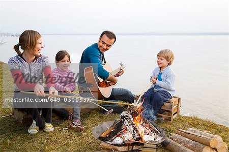 deux filles, garçon et l'homme griller des saucisses