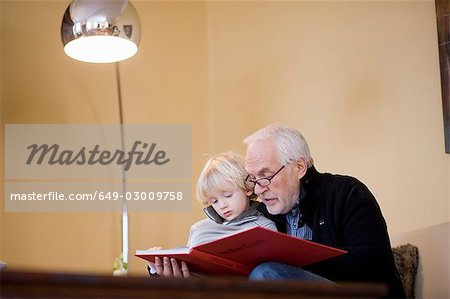 old man reading book to young boy