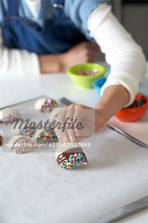 Femme fabriquant de chocolat plongé sablés avec paillettes Femme fabriquant de chocolat plongé sablés avec paillettes