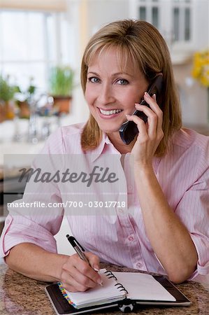 Femme parlant sur un téléphone et écrit dans le carnet de RDV