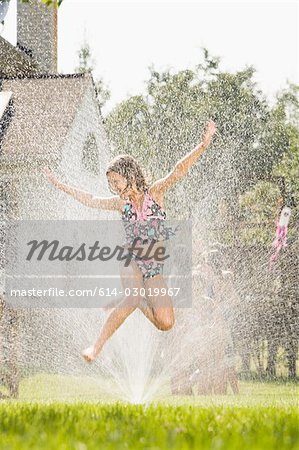 Girl jumping in sprinkler