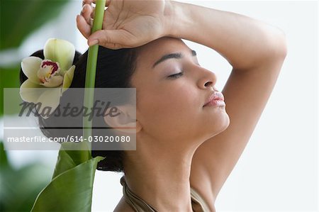 Jeune femme avec des feuilles et des fleurs dans les cheveux