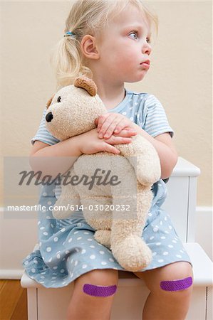 Mädchen mit Teddybär und Putze auf Knien