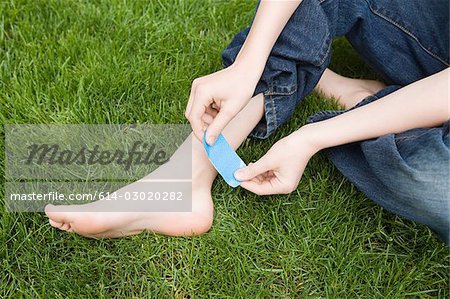 Child putting plaster on ankle