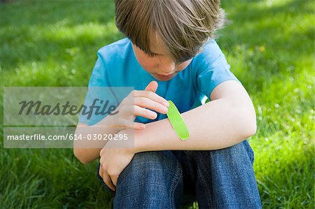 Boy putting plaster on arm