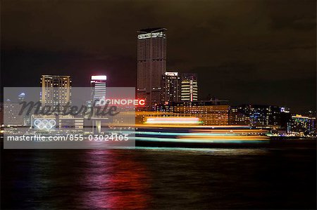 Skyline de Tsim Sha Tsui East pendant la nuit avec un bateau de tourisme au premier plan, Hong Kong