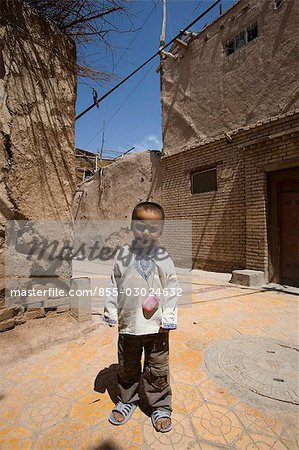 Un garçon ouïghour, debout devant la maison, vieille Kachgar, Xinjiang Uyghur, district autonomie, Silkroad, Chine