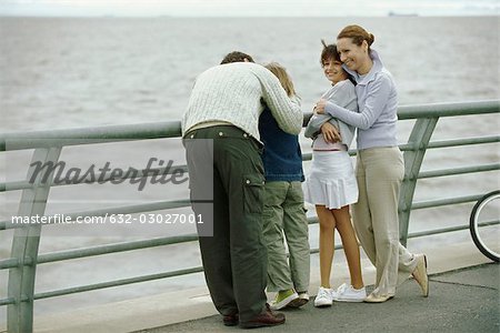 Famille ensemble au bord de mer, embrassant des enfants, des parents père fils réconfortant