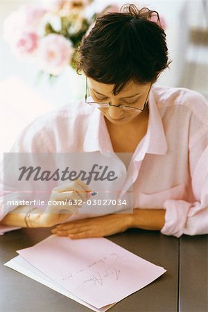 Woman writing and reviewing correspondence