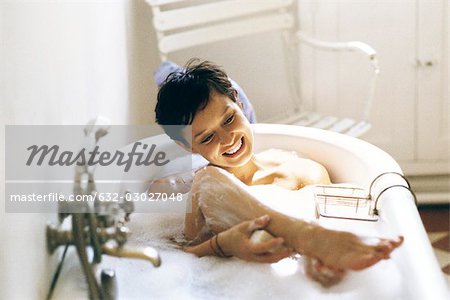 Woman enjoying bubble bath, washing raised leg
