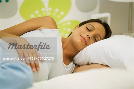 Enceinte femme allongée, main sur le ventre