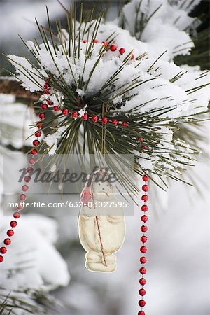 Schneemann-Christbaumkugel und Perlen Girlande von Schnee bedeckten Ast hängend