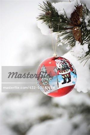 Colorful Christmas ornament hanging from snow-covered branch