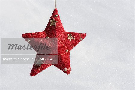 Star Christmas ornament hanging against snowy background