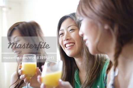 Three young women drinking orange juice