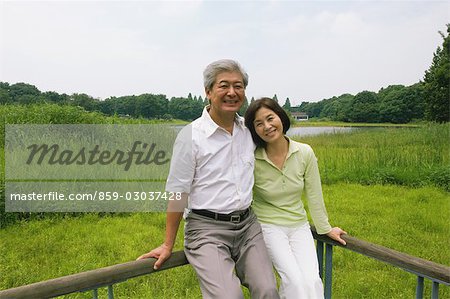 Older Couple Sitting on Wooden Post