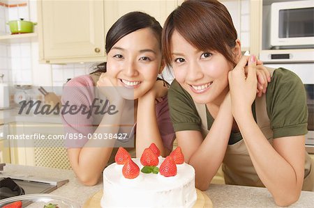 Front view of smiling young women with strawberry cake