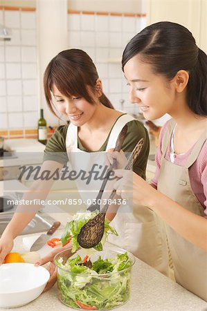 Side view of young women pouring salad