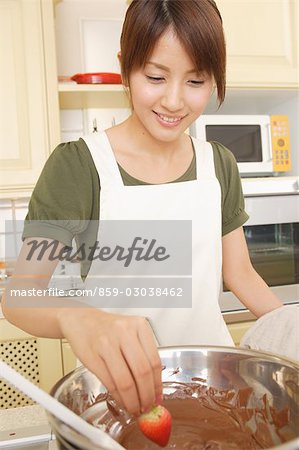 Frontansicht einer jungen Frau, eintauchen, Erdbeeren in Schokolade fondue