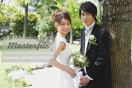 Bride and Groom Standing by Tree