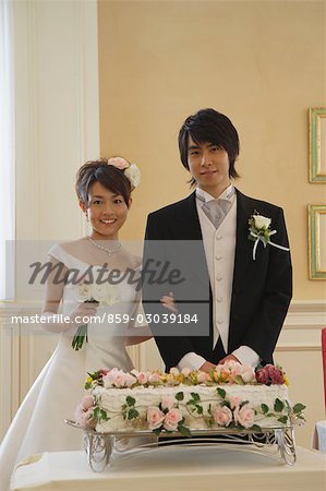 Bride and Groom debout derrière un gâteau