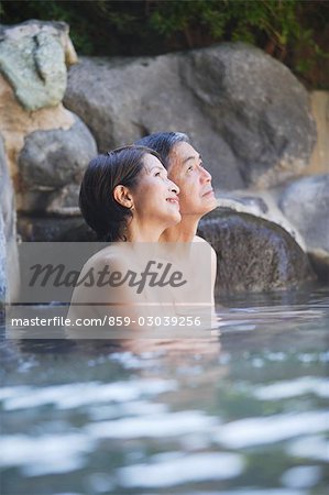 Middle-aged couple relaxing in natural hot spring