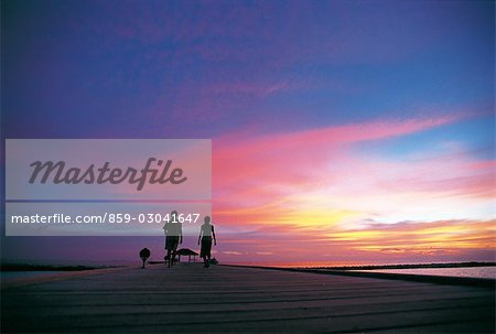 Couple marchant sur une plage au coucher du soleil
